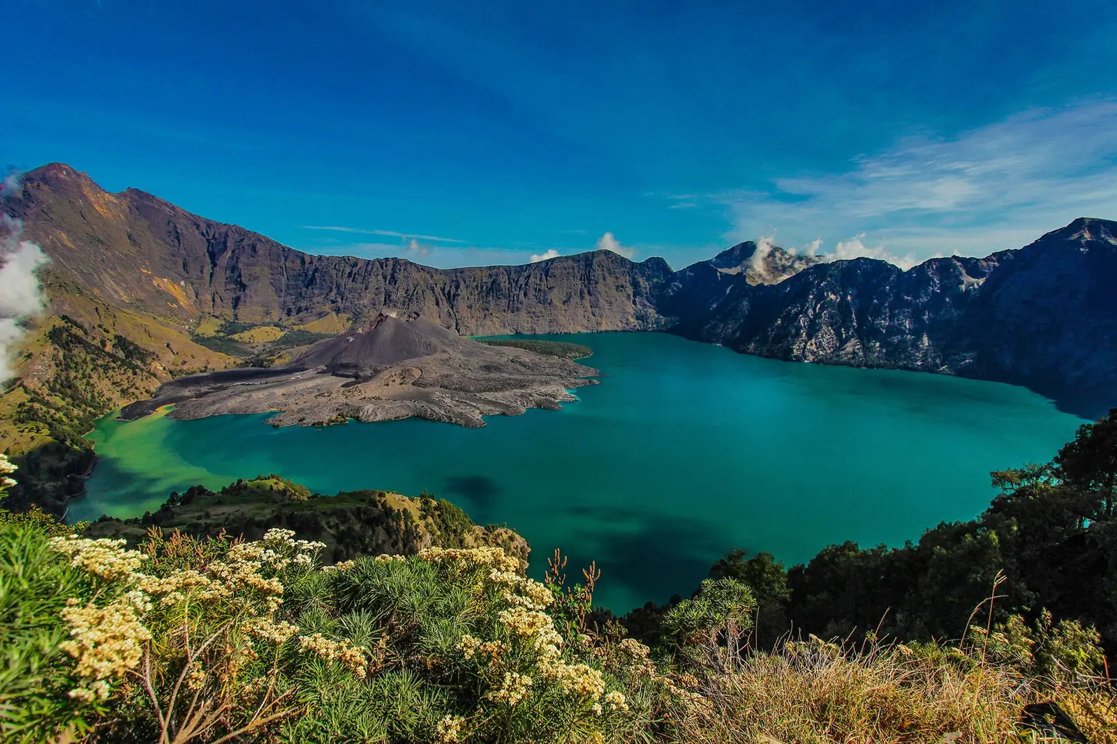 Turquoise Segara Anak crater lake below the steep caldera walls of Mount Rinjani
