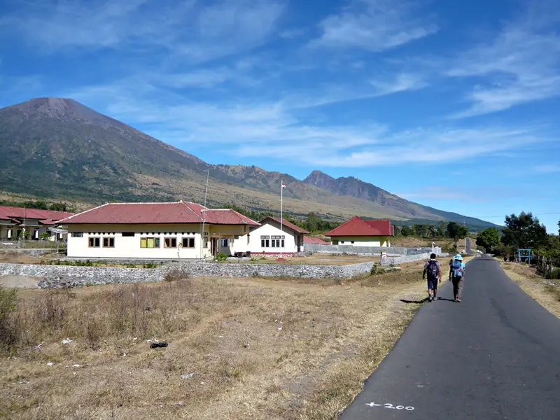 Hikers walking the road through Sembalun Lawang, with Mount Rinjani behind